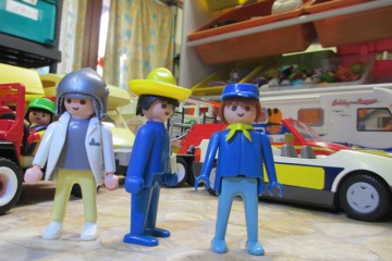 trois playmobil devant des vehicules