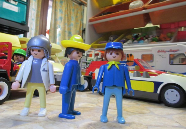 trois playmobil devant des vehicules