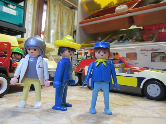 trois playmobil devant des vehicules